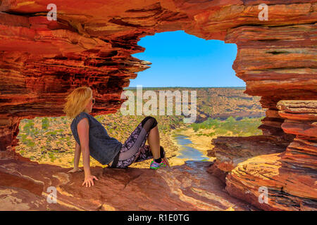 Kaukasische Frau im Rock arch im roten Sandstein von der Natur für Fenster, Blick auf den Murchison River im Kalbarri Nationalpark, Western Australia. Australien reisen Outback. Stockfoto