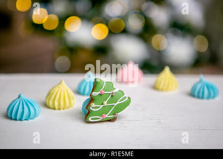 Lebkuchen Tanne und meringue auf dem Tisch vor Defokussierten Lichter von Weihnachten dekoriert Tanne. Urlaub Süßigkeiten. Neues Jahr und Thema Weihnachten. Festliche Stimmung. Weihnachtskarte Stockfoto