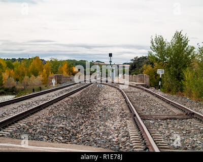 Kreuzung auf Schienen, die durch eine Landschaft im Herbst gehen mit Wolken im Himmel Stockfoto