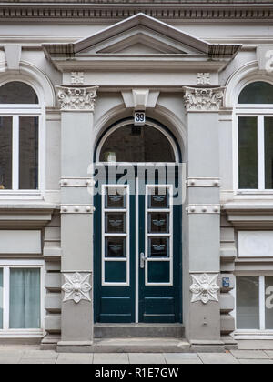 Historische gewölbten Tür mit geschnitzten Paneelen, Architrav und Verzierung auf einem alten Gebäude aus Stein, das auf eine Straße. Stockfoto