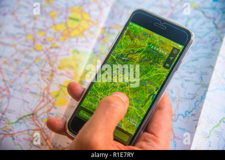 Des Menschen Hand mit Smartphone zeigt eine Karte gegen eine Road Map. Ansicht schließen. Stockfoto