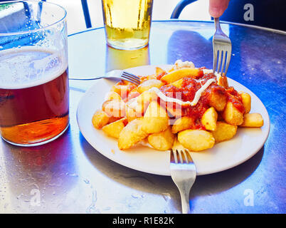 Ein Teil der Patatas Bravas über eine metallische Tabelle. Bratkartoffeln mit würziger Sauce, eine der häufigsten typische spanische Tapas. Stockfoto