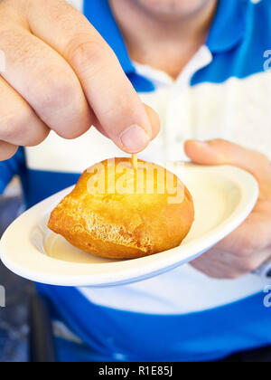 Ein Mann schmeckt ein Bola de carne Pincho, gebratene Fleischbällchen in Teig, typisch von Baskenland kulinarische. Spanien. Stockfoto