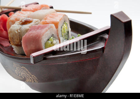 Nahaufnahme der sashimi Sushi mit Stäbchen und Soja auf einem schwarzen, das Boot Fach eingestellt Stockfoto
