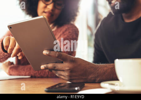 Nahaufnahme von einem Geschäftsmann und Geschäftsfrau zusammen bei der Arbeit sitzen auf einen Tablet-PC. Mann hält einen Tablet-PC, während eine Geschäftsfrau Stockfoto