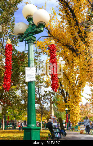 Im Herbst Laub ändern, und roter Chili ristras hängen von der Lampe posy, Menschen schlendern und die Plaza im Zentrum der Innenstadt von Santa Fe, NM genießen Stockfoto