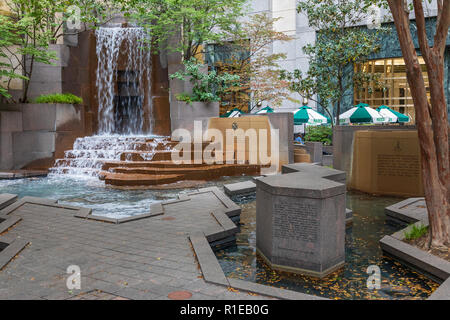 CHARLOTTE, NC, USA -11/08/18: eine kleine City Park mit Wasserfall, und Essplatz im Reid's im Hintergrund. Stockfoto