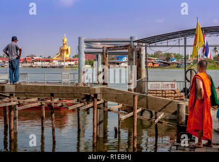 Ein Mönch und ein Thailändisches Mann auf einem Dock am Großen Buddha Figur über den Fluss suchen. Stockfoto