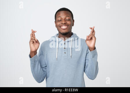 Junge afrikanische Mann, einen Wunsch auf weißem Hintergrund. Ich möchte alles, was ich brauche, zu erhalten. Stockfoto