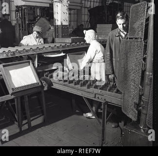 1950, historische, weibliche Arbeitnehmer tragen Overalls und Haarnetze in der Fabrik in der Fabrik arbeiten, immer bereit, Batterie, Wald Rd, London, England, UK. Stockfoto