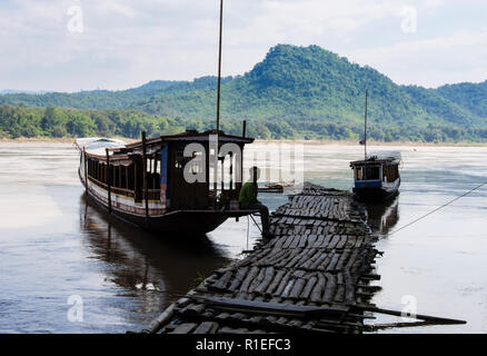 Boatman darauf wartet, von touristischen Boote von Fadenscheinigen Holzsteg an Tham Ting Höhlen auf Mekong vertäut. Pak Ou, Provinz Luang Prabang, Laos, Asien Stockfoto