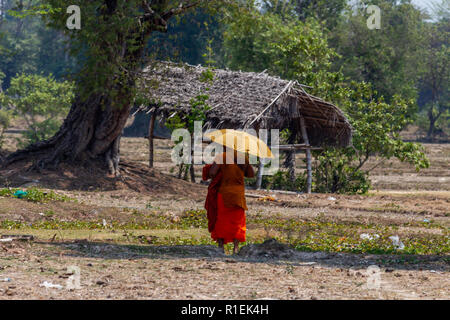 Don Det, Laos - 22. April 2018: buddhistischer Mönch mit einem Schirm vor der Sonne zu schützen und zu Fuß zu einem Pfad in der Nähe von Don Det Dorf in Laos. Stockfoto