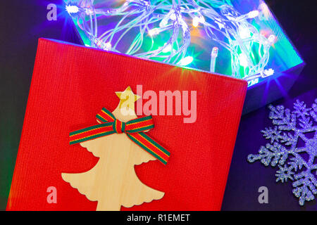 Geschenkbox in Rot mit einer Girlande der Lichter für ein Geschenk für das neue Jahr oder Geburtstag. Close-up Stockfoto