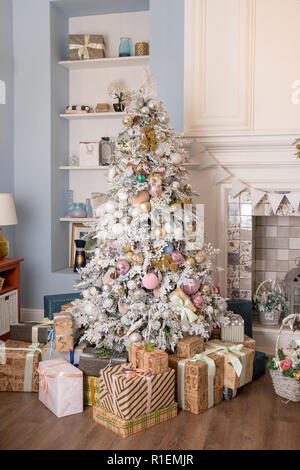 Innenbereich Wohnzimmer mit einem Weihnachtsbaum und Dekorationen. Schönen Urlaub eingerichtete Zimmer mit Weihnachtsbaum mit Geschenken darunter. das Neue Jahr mit einer Tanne in Weiß, Pastelltönen Stockfoto