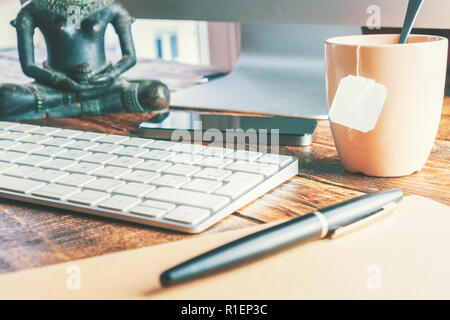 Büro Schreibtisch close-up mit Tastatur und einer Tasse Tee. Arbeit Büro Konzept. Stockfoto