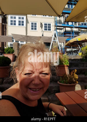 Lüneburg, Niedersachsen, Deutschland - 28. JULI 2017: Frau sitzt im Biergarten der ein Restaurant in Lüneburg und lachend in die Kamera Stockfoto