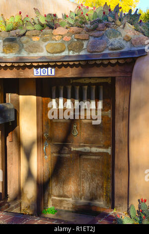 Eine alte Adobe Haus mit Prickly Pear Kakteen auf einem alten hölzernen vintage Eingangstür bei Sonnenuntergang in einem historischen Viertel in Santa Fe, NM, USA Stockfoto