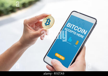 Hand mit gold Bitcoin bezahlen Rechnung Online Store auf mobile App. digitale Währung. Banking Finanzielle Technologie. akzeptiert Bitcoin hier Stockfoto