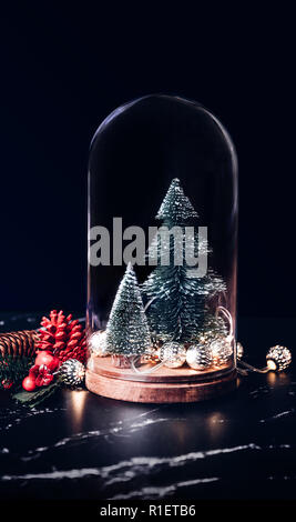 Frohe Weihnachten mit Mistel und Geschenkbox Symbol mit Xmas Tree und sanftes Licht string und Pine Cone Dekoration auf Marmor tisch und blauer Hintergrund Stockfoto