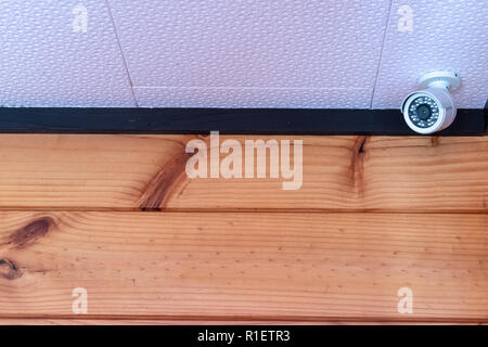 Home security Kamera in die Ecke der weißen Decke und Holz Wand installiert Stockfoto