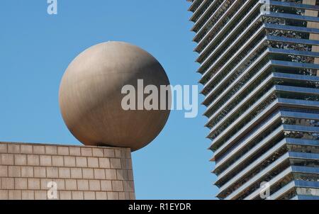 Die Esfera (Kugel) Skulptur von dem Architekten Frank Gehry in Port Olimpic in Barcelona, Spanien am 17. April 2018. Die Mapfre Turm ist im Hintergrund. Stockfoto