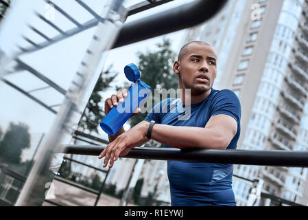 Junge afrikanische Mann am open air Gym ruht sich mit Wasser Stockfoto
