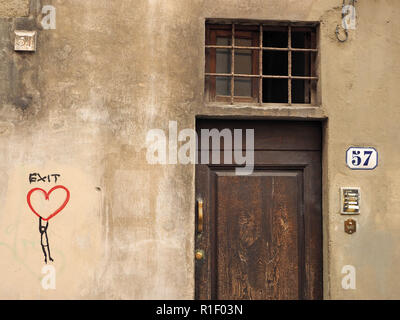 Holz Tür Nr. 57 mit Messingbeschlägen Türklingeln &-Zeichen auf der einen Seite, Graffiti Artwork auf der anderen Seite im Stadtzentrum Straße in Florenz, Italien Stockfoto