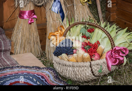 Große reife Äpfel, Trauben, Beeren und Gemüse werden in schön dekorierten Weidenkorb auf der Messe verkauft. Stockfoto