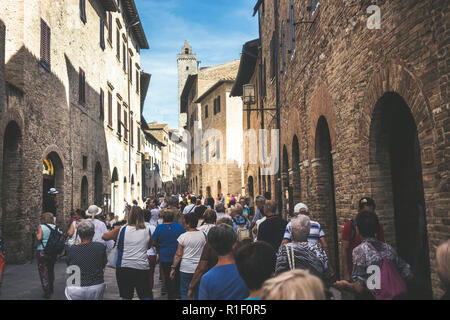 Masse der Touristen Menschen gehen zusammen gezogen und mit der Straße voll in San Gimignano in der Provinz Siena in der Toskana, Italien. Urlaub und Kultur in einem med. Stockfoto