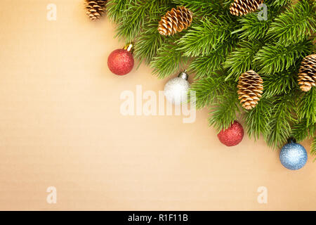 Weihnachten und ein glückliches Neues Jahr Ecke Hintergrund für die Postkarte. Fir-Zweige, Kegel und Kugeln auf einem hellen Hintergrund. Stockfoto