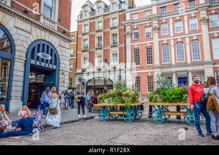 Touristen ihre Zeit am Covent Garden Market, einem der beliebtesten Einkaufsviertel und touristischen Sehenswürdigkeiten in London, Vereinigtes Königreich Stockfoto