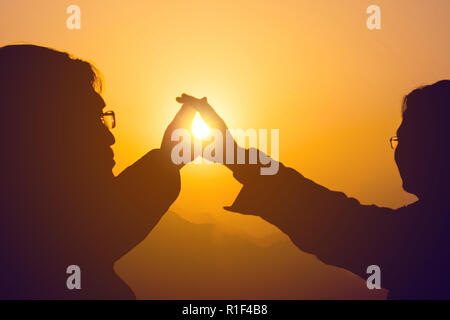Zwei Männer erreichen die Hände zur goldenen Sonne über die Berge am Morgen, Freund, Partner, Zusammenarbeit. Stockfoto