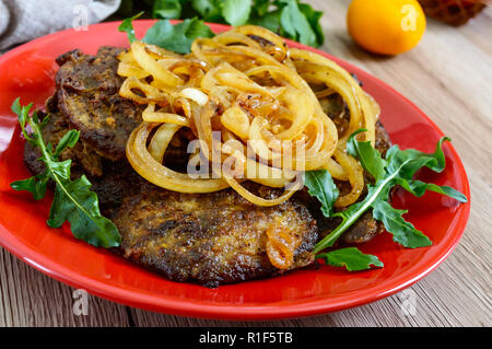 Saftige Scheiben gebratene Leber und Zwiebeln auf einem roten Schild. Stockfoto