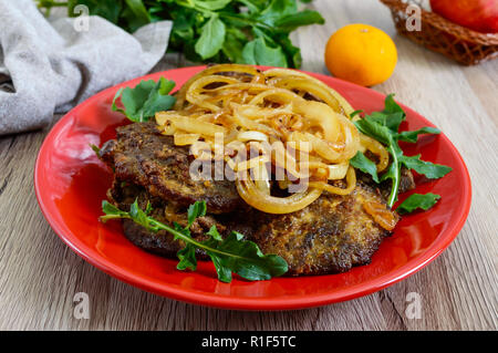 Saftige Scheiben gebratene Leber und Zwiebeln auf einem roten Schild. Stockfoto