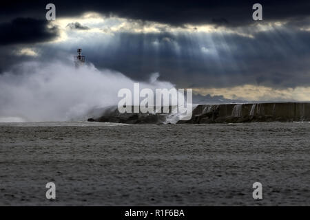 Gewitter bei Sonnenuntergang mit grossen Meer plantschen und windigen Wellen über Pier und Rundumleuchte. Mündung des Flusses vom Norden von Portugal. Erweiterte Himmel. Stockfoto