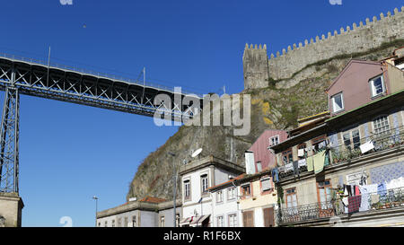 Detaillierte Foto von Oporto Granit zu sehen, die mittelalterliche Stadtmauer mit Turm und Zinnen und einer seiner alten Eisernen Brücken gegen schönen tiefblauen Himmel. Stockfoto