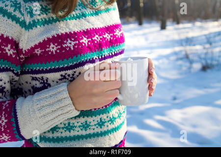 Junge Frau hält Tasse Kaffee mit Marshmallow im Winter Wald Stockfoto