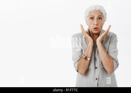 Oma besorgt Sohn erhielt dünn. Portrait der nervösen schockiert und betroffen Art charmante Senior Frau mit weißen Haaren keuchend Holding Palmen in der Nähe von Gesicht in w Stockfoto