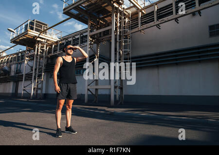 Junge Athlet Mann für Betrieb und weg schauen auf industrielle Gebäude Hintergrund vorbereiten Stockfoto