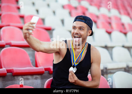 Sieger mit Medaillen, selfie mit Zunge. Meister nimmt Moment des Triumphes. Sieg Konzept Stockfoto