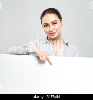 Happy Geschäftsfrau zeigen und Holding weiße Leere namensschild Hintergrund. Junge Frau lächelnd, Business und Bildung Konzept Stockfoto