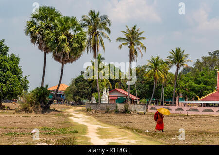 Don Det, Laos - 22. April 2018: buddhistischer Mönch mit einem Schirm vor der Sonne zu schützen und zu Fuß zu einem Pfad in der Nähe von Don Det Dorf in Laos. Stockfoto