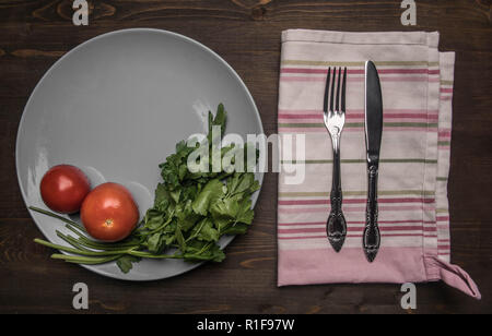 Einfaches Essen, Tomaten, Petersilie und Nudeln auf einem grauen Platte, auf einer hölzernen Hintergrund gesäumt, Ansicht von oben Stockfoto