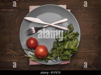 Einfaches Essen, Tomaten, Petersilie und Nudeln auf einem grauen Platte, auf einer hölzernen Hintergrund gesäumt, Ansicht von oben Stockfoto