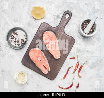 Zwei köstliche roher Lachs Steaks mit Zitrone, Pfeffer würzen und auf einem weißen Hintergrund, Ansicht von oben Stockfoto
