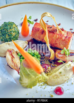 Lende von Kaninchen mit Gemüse gefüllte Knödel und Pease und Karotten auf schwarz-Sauce. Stockfoto