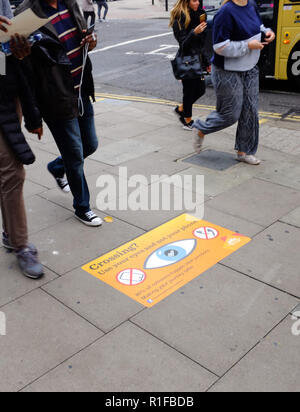 Straße Bürgersteig Zeichen, die Fußgänger achten, überqueren Sie die Straße und nicht auf ihre Telefone für Musik hören über Kopfhörer in Brighton, UK suchen Stockfoto