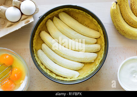 Vorbereitung Bananenkuchen (Käsekuchen), die von den Zutaten auf hölzernen Tisch Hintergrund. Flach. Ansicht von oben. Stockfoto