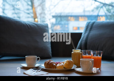 Dunkler Küchentisch mit Frühstück. Frisch gebackene Croissants, Erdnussbutter und Kaffee auf rustikalen Holzbrett über Dark grunge Kulisse. Stockfoto