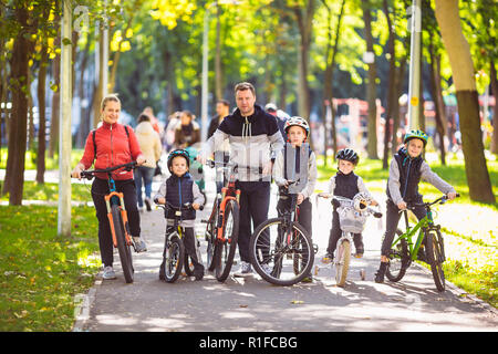 Thema Familie Sport aktiv Erholung im Freien. Eine Gruppe von Menschen ist eine große Familie von 6 Personen stehen auf Mountainbikes in einem Stadtpark auf einer Roa posing Stockfoto